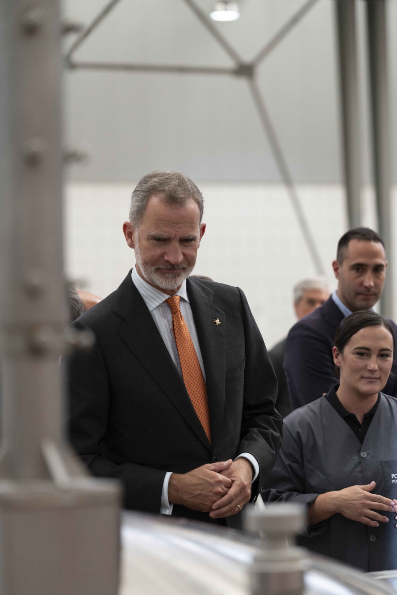 El rey observa el funcionamiento de la esmaltadora de una la planta que ha visitado.